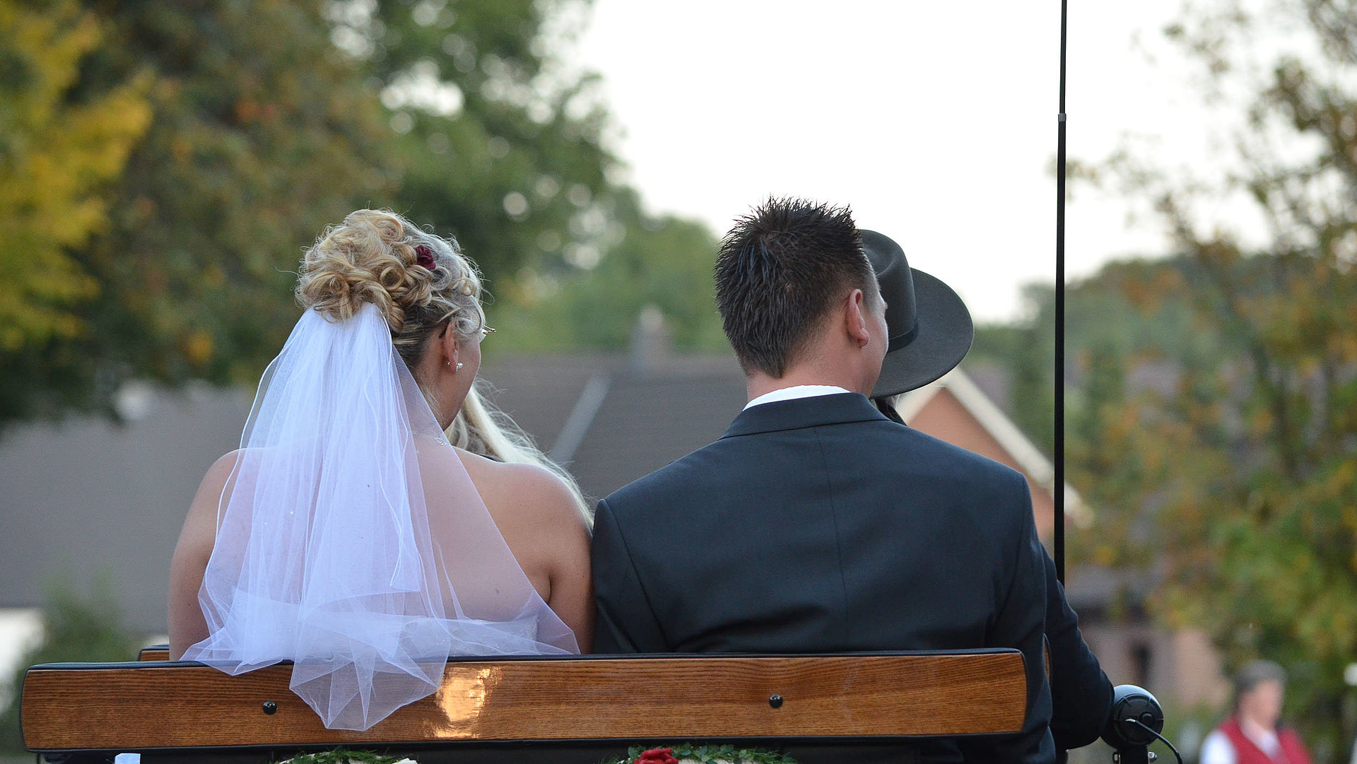 Heiraten in der Fränkischen Schweiz - Brautpaar sitzt auf Holzbank mit Rücken zur Kamera