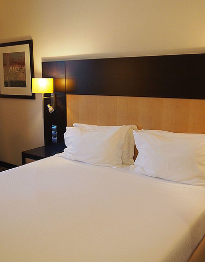 Unterkunft für Geschäftsreisende in Oberbayern  - sehr ordentliches Hotelzimmer mit großem Bett, warmer Nachtlampe und mittelgroßem Wandgemälde