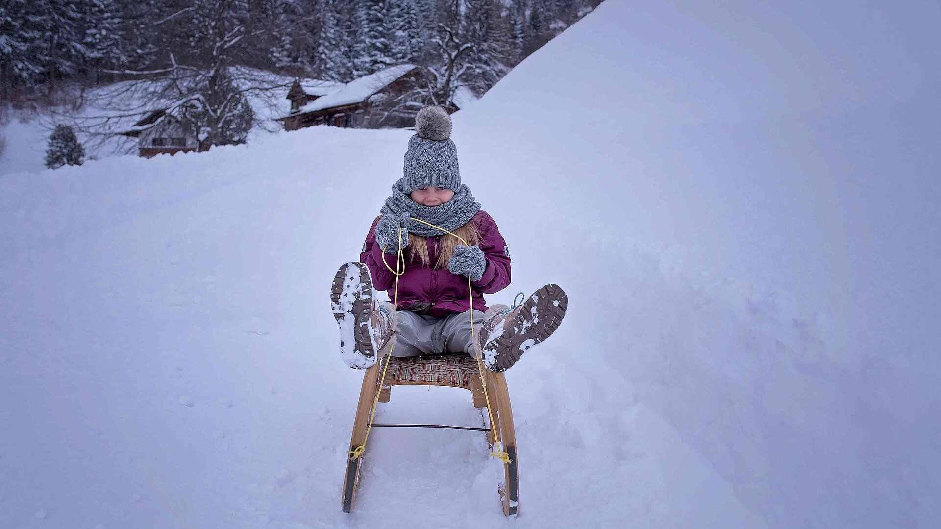 Winterrodelbahnen im Oberallgäu - Kind auf einem Schlitten im Schnee