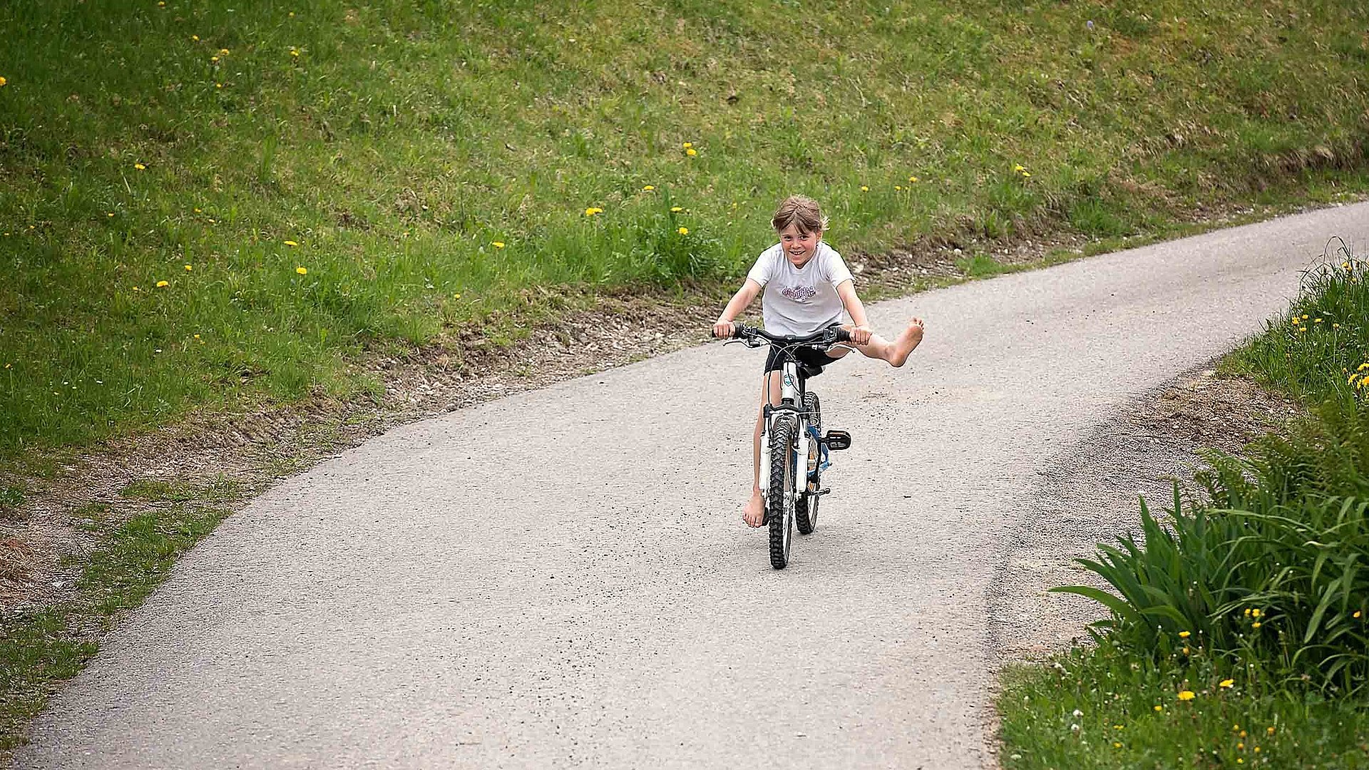 Radfahren und Radwandern im Ostallgäu - kleiner Junge fährt neben Wiesen Mountainbike
