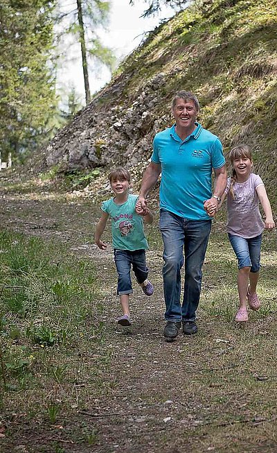 Wandern und Wanderurlaub - drei-köpfige Familie; Mann mit Kleinkindern, zwei Mädchen; im Waldgebiet auf Wanderweg